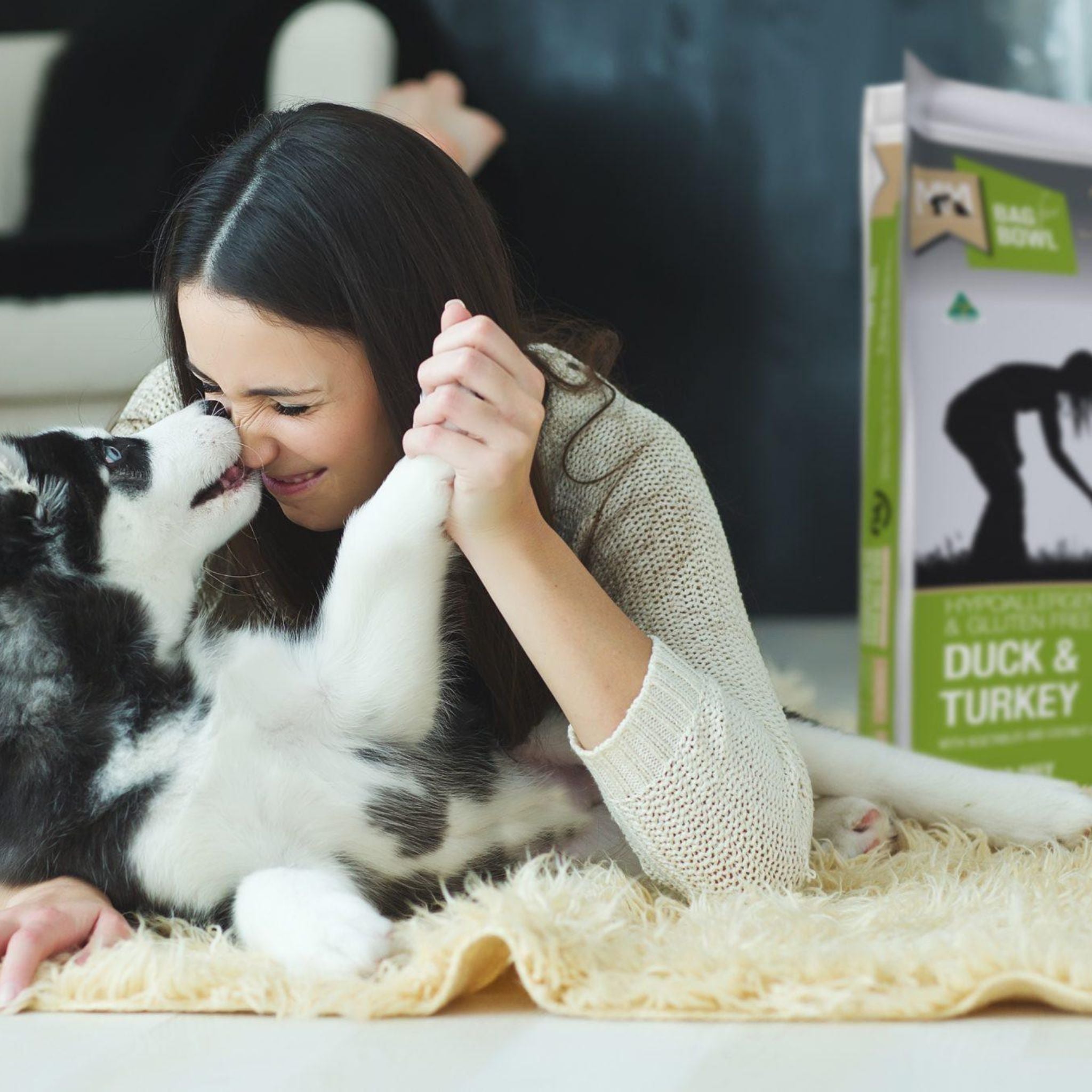 Lady interacting with a dog - a green and silver bag of Duck and Turkey dog food in the background