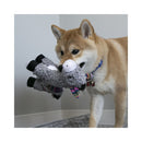Medium sized dog happily carrying a grey KONG Sherps Donkey plush toy in its mouth indoors.