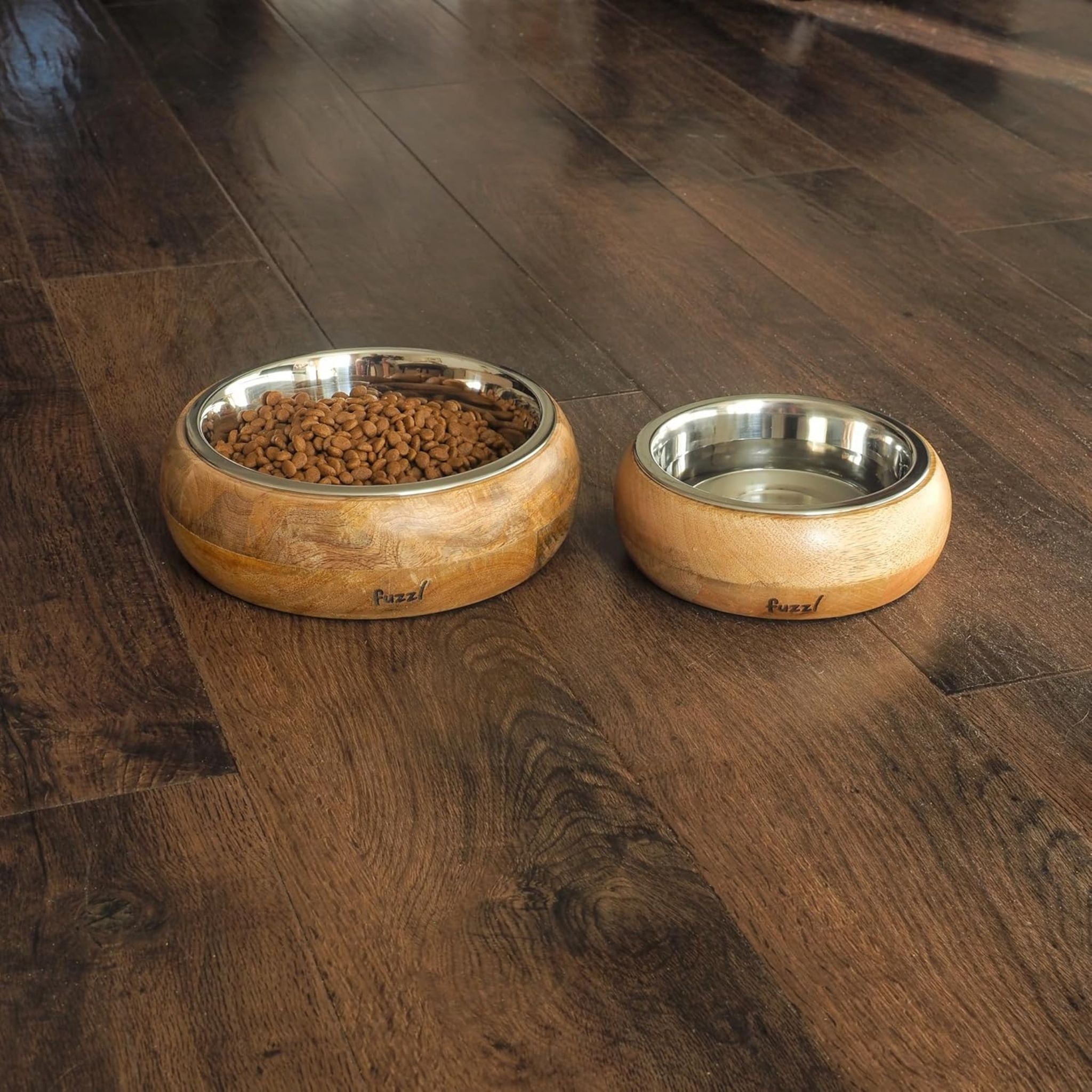 Pair of Fuzzl Titan Mango Wood & Stainless Steel Dog Bowls on timber floor, one filled with kibble, one with water.