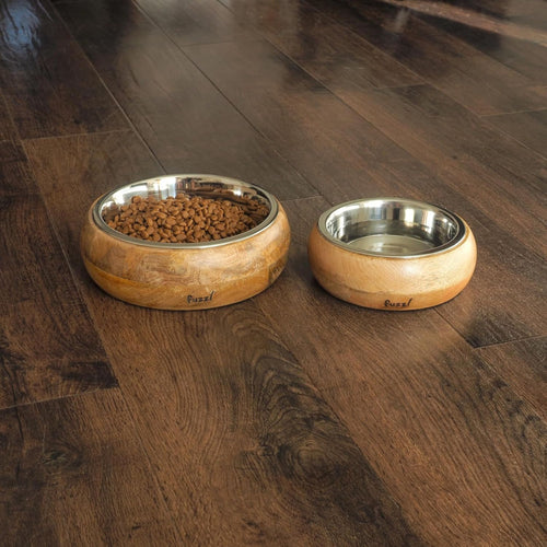Pair of Fuzzl Titan Mango Wood & Stainless Steel Dog Bowls on timber floor, one filled with kibble, one with water.