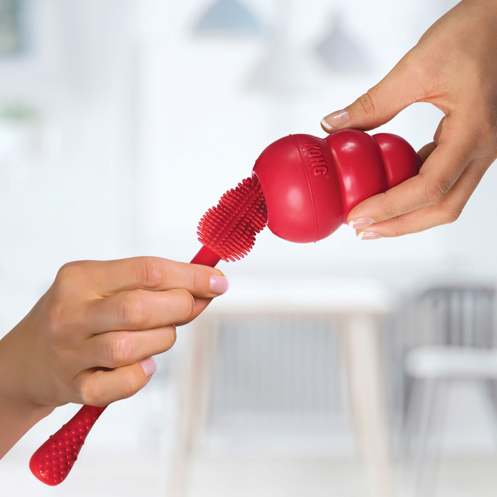 Person using the KONG Brush to clean a KONG Classic dog toy