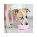 Puppy licking treats stuffed inside a Pink KONG Puppy Tires dog toy during indoor enrichment play.