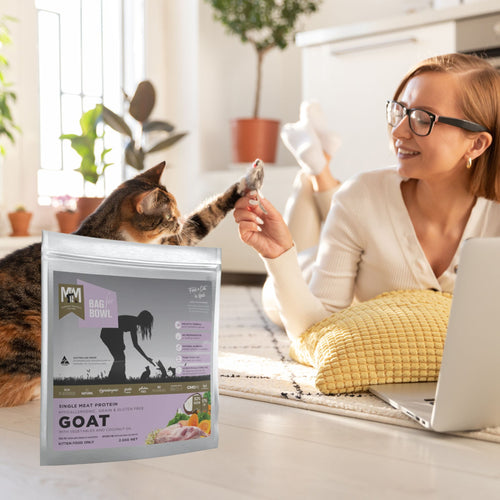 Woman with a cat and a bag of single-protein goat kitten food on the floor
