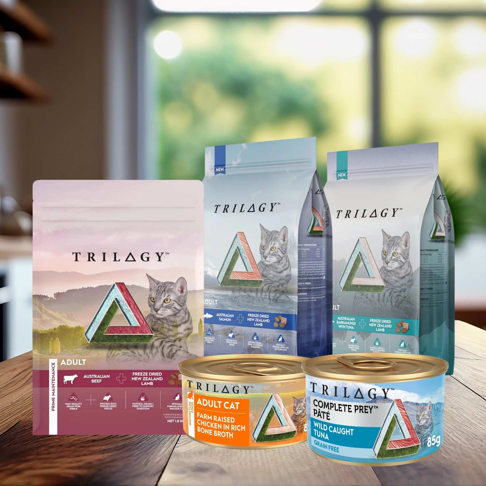 Trilogy ultra-premium dry and wet cat food packaging on a wooden kitchen counter.