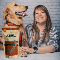 Lifestyle image of a happy pet owner and dog featuring a pack of Zeal Free Range Spare Ribs Treats for Dogs.