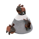 A plush brown and grey Elk Mountain dog toy with one mini plush elk perched on top, another elk head peeking out from a burrow hole, and a third mini elk standing next to the mountain.