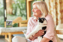 Smiling lady holding a cat. A bag of Meals for Meows Single Meat Protein Duck cat food in the background.